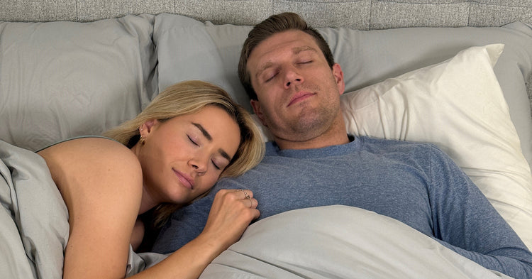 Couple sleeping together in bed with gray bedding